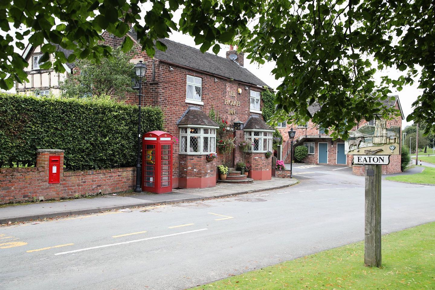 The Plough Inn, a red-brick Cheshire inn beside the Eaton village sign